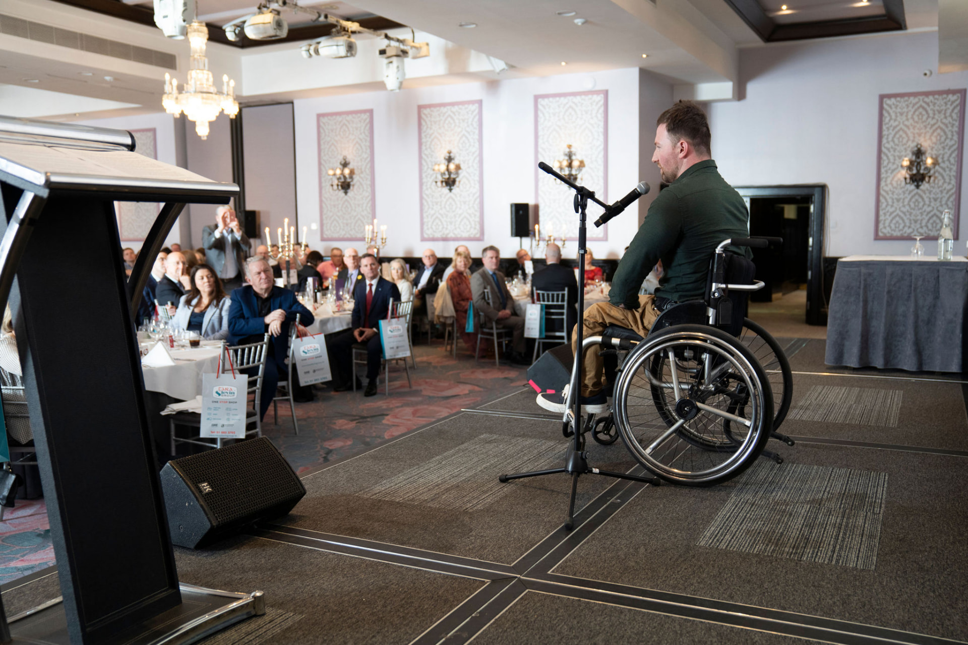 Colin Judge addressing a seated business audience at a corporate anniversary event